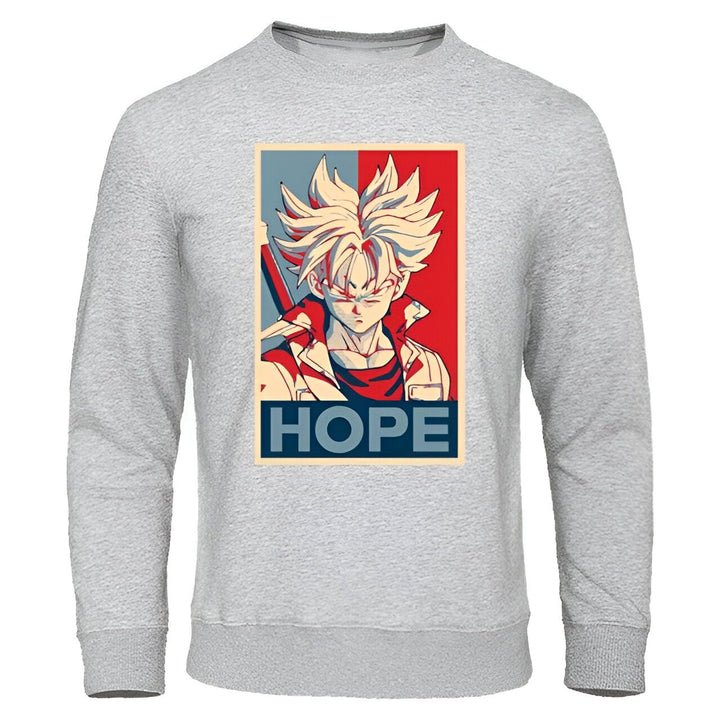 Le sweat-shirt gris présente un portrait de Trunks du futur, un personnage de Dragon Ball Z. Il est représenté de face, avec ses cheveux blonds hérissés et ses yeux bleus. Il porte une veste bleue et une chemise orange. Le texte "Hope" (espoir) est écrit en rouge et en bleu sous le portrait.