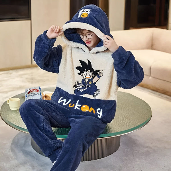 Une personne portant un pyjama bleu et blanc à capuche avec un personnage de dessin animé dessus. Il est assis sur un canapé et porte des lunettes. Il y a une table basse devant lui avec une tasse et une assiette dessus.,PY-0811324532,PY-5509675837,PY-5569443193