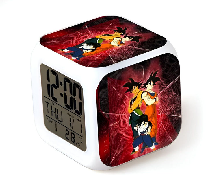 L'image montre un réveil numérique avec une image de Son Goku, un personnage de la série animée Dragon Ball Z. Le réveil est de couleur blanche et possède un écran LED rouge. Il est posé sur une surface noire.,RS-9384048089