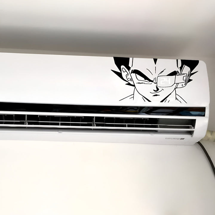 L'image représente un sticker mural en vinyle d'un personnage de dessin animé, Vegeta, de la série Dragon Ball Z. Le sticker est noir et représente le visage de Vegeta, avec ses cheveux noirs hérissés et son regard déterminé. Il est placé sur un mur blanc, au-dessus d'un climatiseur.,ST-0212265520