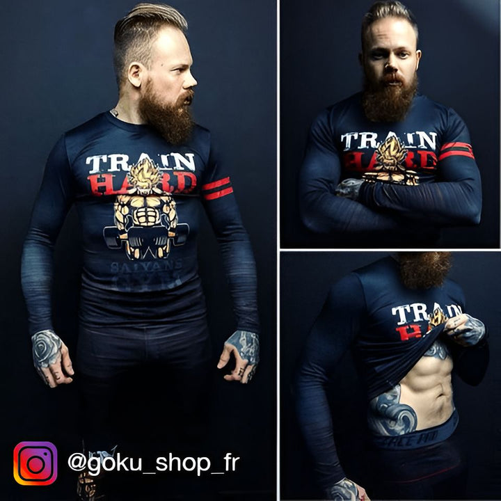 L'image montre un homme barbu portant un rashguard noir avec des motifs rouges. Le rashguard a un col rond et des manches longues. L'homme est debout, les bras croisés sur la poitrine. Il a l'air sérieux et déterminé. En arrière plan, on peut apercevoir un mur en briques rouges.,T--0876623224,T--2115446925,T--7783549241,T--8698563430,T--4045379827,T--3542155292