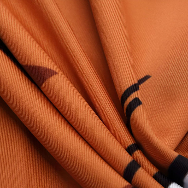 Une image en gros plan d'un tissu orange avec des motifs géométriques noirs.,T--7663222652,T--5989670826,T--9442091786,T--8470437577,T--7431847505,T--4599751499,T--9963113028,T--6402756075
