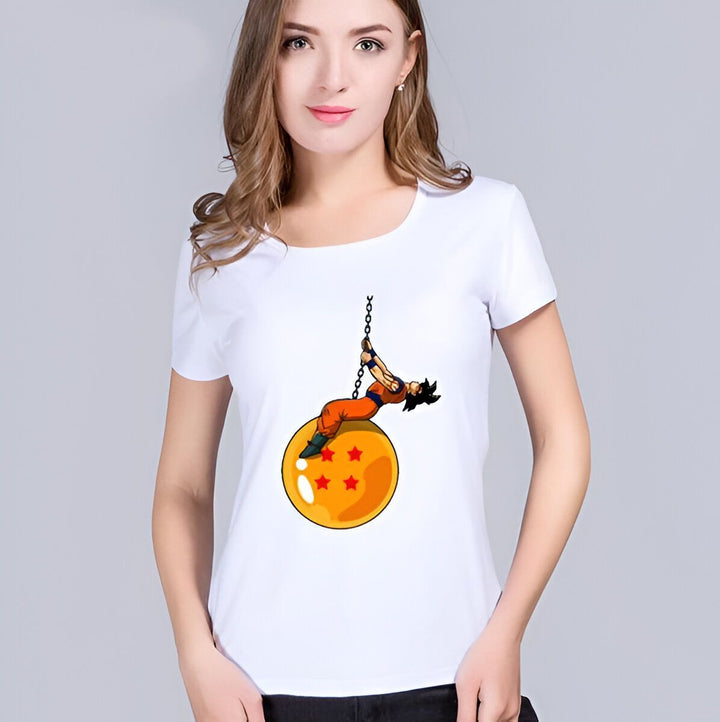 Une femme porte un t-shirt blanc avec un dessin de Son Goku, un personnage de Dragon Ball Z. Son Goku est suspendu à une boule de cristal orange avec des étoiles rouges.,T--4863784503,T--589376434X,T--167175302X