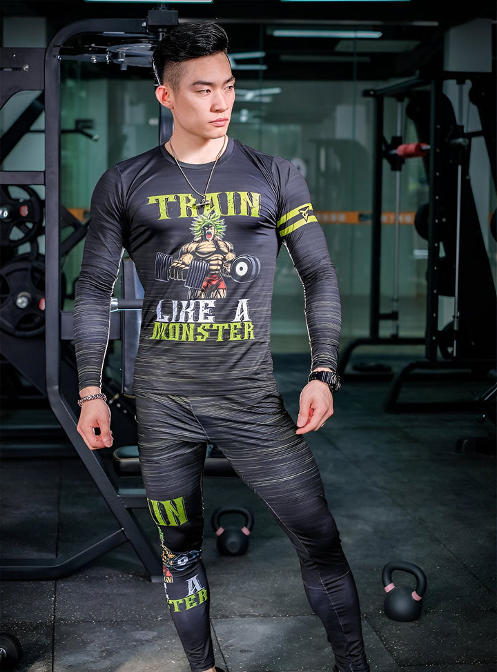 L'image montre un homme vêtu d'une tenue de sport noire et verte. Il porte un t-shirt moulant à manches longues avec l'inscription "Train like a monster" et un pantalon de sport moulant. Il est debout dans une salle de sport, entouré d'appareils de musculation.,TE-9158478906,TE-1245081071,TE-5000455452,TE-8947299146,TE-6230729628