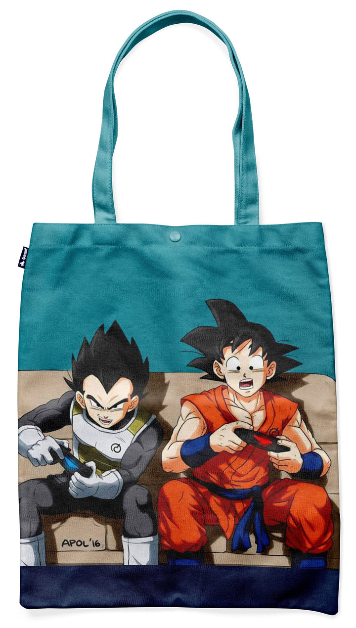 L'image représente un sac fourre-tout en toile de couleur bleu turquoise avec une image de Goku et Vegeta, deux personnages de la série animée Dragon Ball Z. Goku est assis à gauche, vêtu d'une combinaison orange et bleue, et Vegeta est assis à droite, vêtu d'une combinaison bleue et jaune. Ils sont tous deux en train de jouer à des jeux vidéo, et il y a une manette de jeu vidéo dans la main droite de Goku et dans la main gauche de Vegeta. Le sac fourre-tout est parfait pour transporter des affa