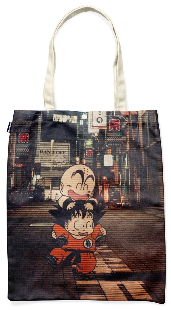 L'image représente un sac fourre-tout en toile de couleur beige avec une illustration de Son Goku et Krilin, deux personnages du manga Dragon Ball Z. Ils sont représentés en train de marcher dans une rue animée avec des bâtiments et des enseignes lumineuses en arrière-plan.,TO-9800270760