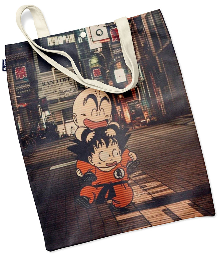 L'image représente un sac fourre-tout en toile de couleur beige avec une illustration de Son Goku et Krilin, deux personnages du dessin animé Dragon Ball Z. Ils sont représentés en train de marcher dans une rue animée avec des bâtiments et des enseignes lumineuses en arrière-plan.,TO-9800270760